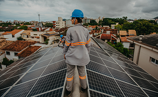 woman installing a solar panel onto a roof