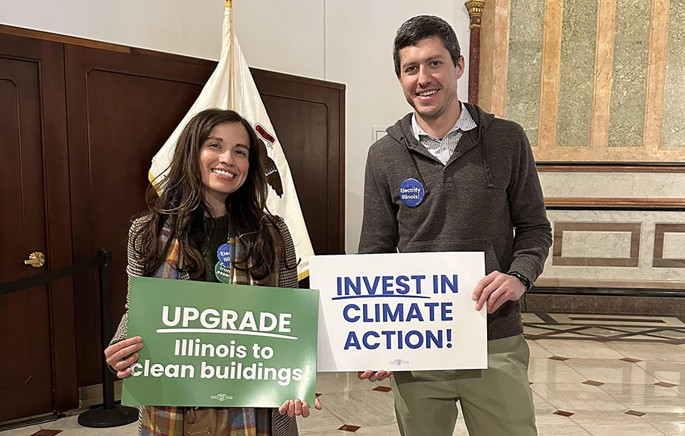 two people holding climate investment signs
