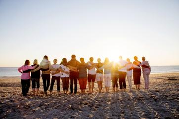 Friends on a beach embracing at sunset