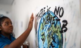 girl writing sign "there is no planet b"