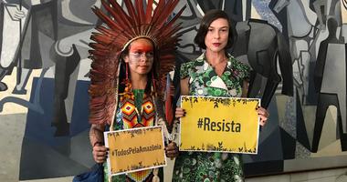 Women holding signs that say resist