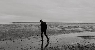 Man walking on dreary beach