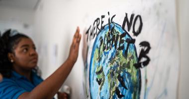 girl writing sign "there is no planet b"