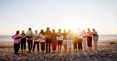 Friends on a beach embracing at sunset