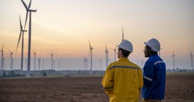 Two men observing a turbine field