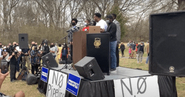 People speaking at a podium at a rally