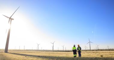 Two people overlooking wind turbines.
