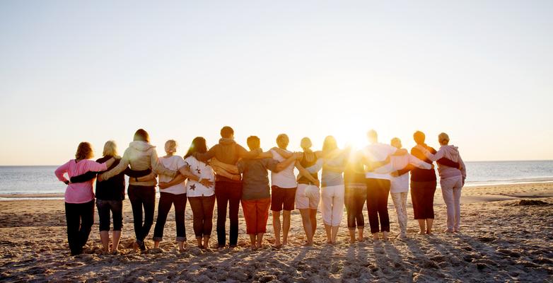 Friends on a beach embracing at sunset