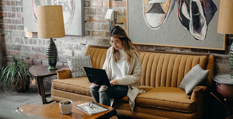 Woman sitting on couch browsing on laptop computer 