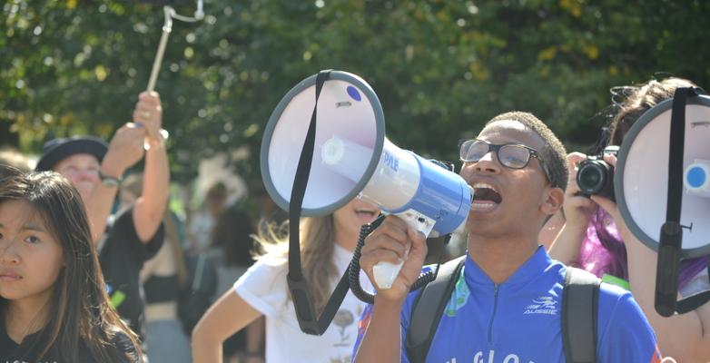 Person in blue shirt speaking into megaphone 