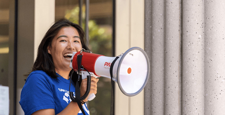 woman in blue shirt speaking into megaphone