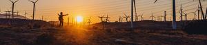 Person walking among turbines at sunset