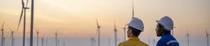 two workers looking at turbines at sunset